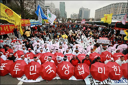 축산농민들이 빨간 우산에 '한미협상 국민투표 실시' 등의 요구사항을 적어서 들고 있다. 